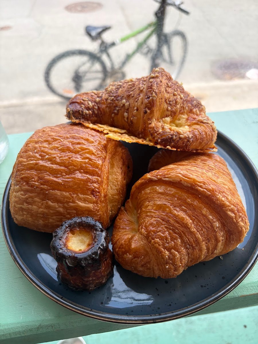Croissants dorés et feuilletés, chocolatine, croissant au fromage et cannelé sur une assiette.